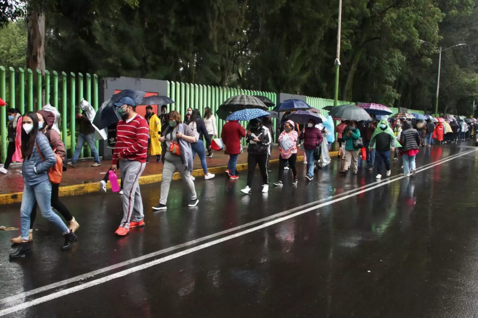 Bajo la lluvia,  jóvenes y persona rezagadas abarrotan el Deportivo Xochimilco para la vacunación contra COVID-19.