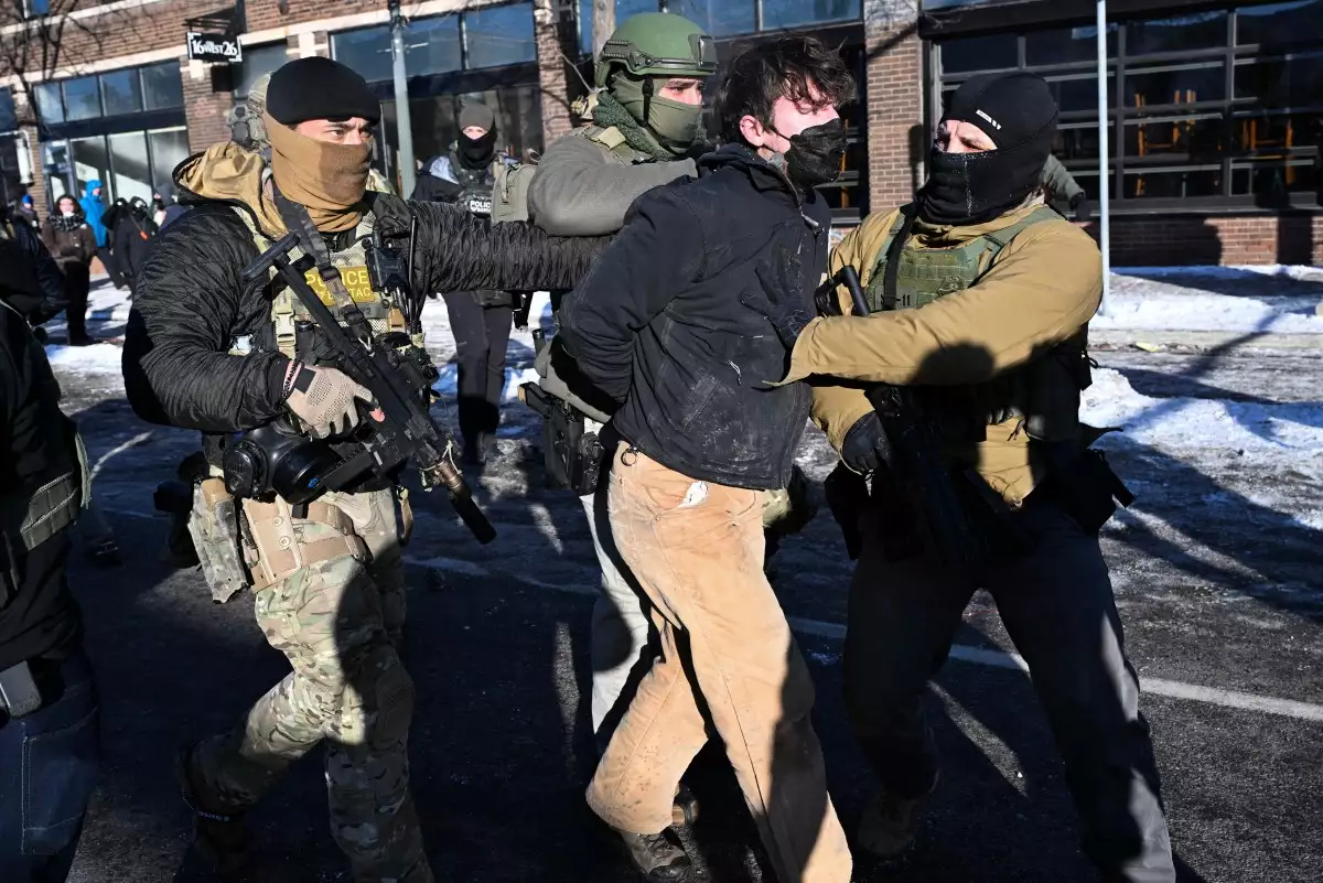 Un hombre es detenido por las fuerzas del orden, cerca del lugar donde las autoridades estatales y locales dicen que un hombre recibió un disparo por agentes federales temprano en la mañana en Minneapolis, Minnesota, el 24 de enero de 2026. El gobernador de Minnesota, Tim Walz, dijo el sábado que los agentes federales desplegados en Minneapolis como parte de una amplia represión de la inmigración habían llevado a cabo "otro tiroteo horrible", menos de tres semanas después del tiroteo fatal de Renee Good.