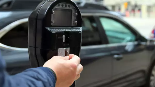 Man is paying  by coins for parking in the street  new with his car