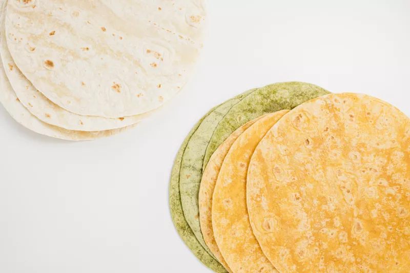 Spanish tomato, spinach flavored and plain wheat tortilla wraps on white background