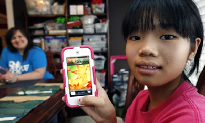 Guan Ya muestra el dispositivo que usa para traducir y comunicarse con su familia adoptiva. (Foto: AP)