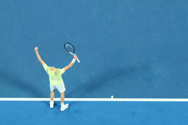 Foto de Jannik Sinner con los brazos levantados y la raqueta en una mano en señal de victoria tras ganar el Abierto de Australia 2025.