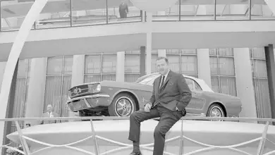Henry Ford II sentado junto al mítico Mustang 1964 que logró catapultar a la marca en el segmento deportivo.