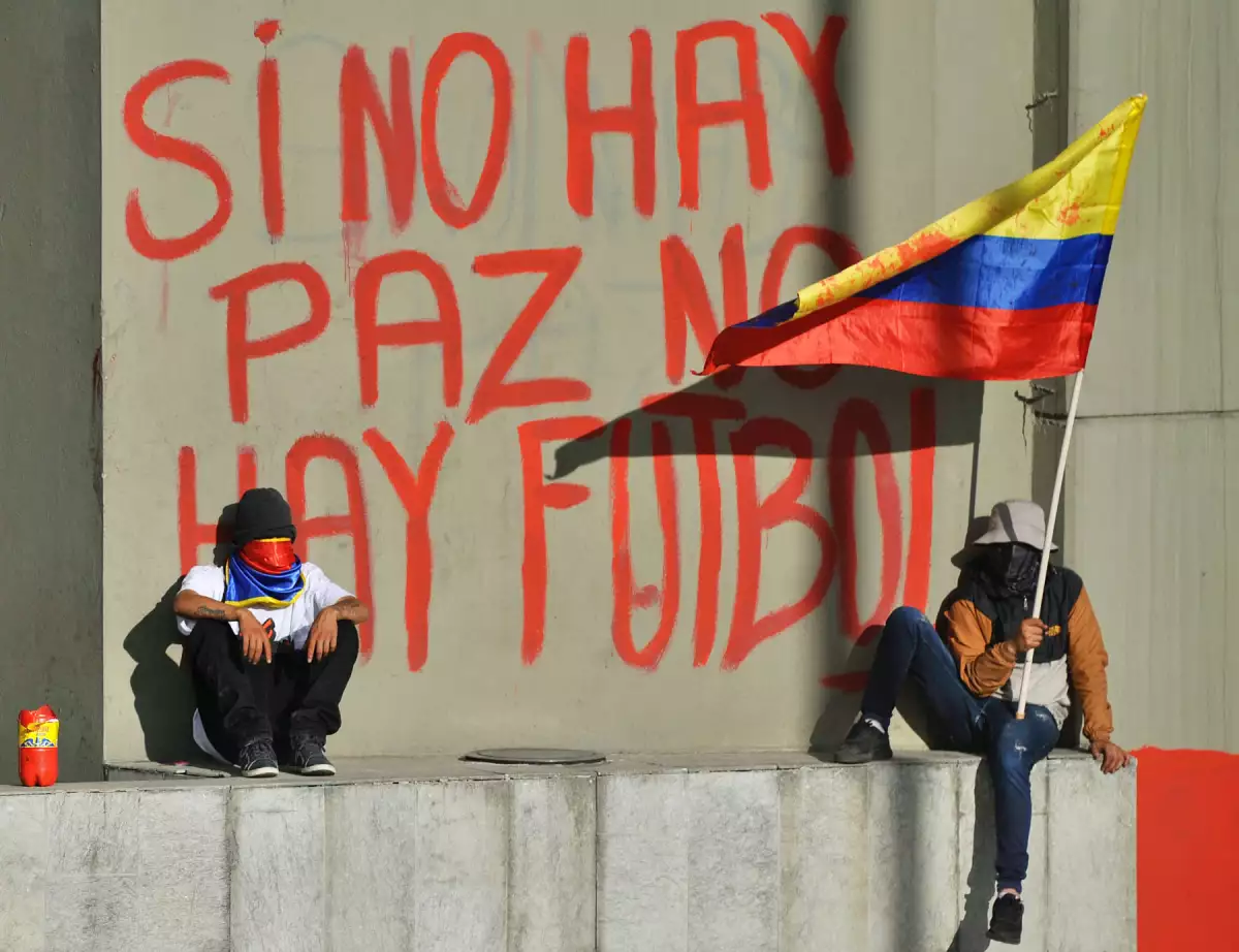 Los manifestantes se sientan junto a un grafiti que dice "Si no hay paz, no hay fútbol" en una pared del Estadio Campin mientras protestan contra Colombia, que alberga el torneo de fútbol de la Copa América durante una huelga nacional el 19 de mayo de 2021 en Bogotá, Colombia, el 19 de mayo de 2021 en Bogotá, Colombia.