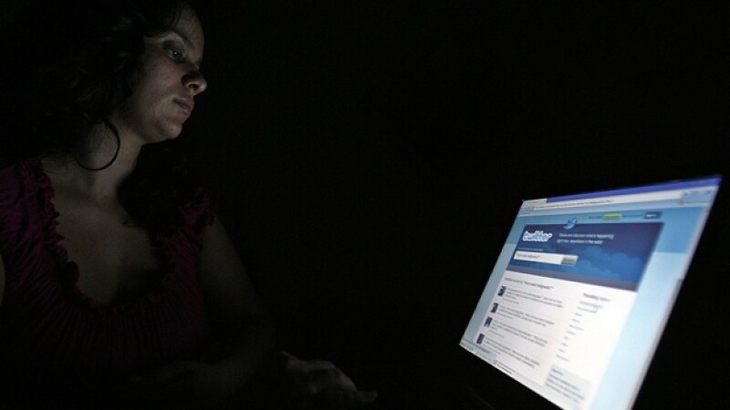 una chava frente a una pantalla donde se ve la pagina de twitter