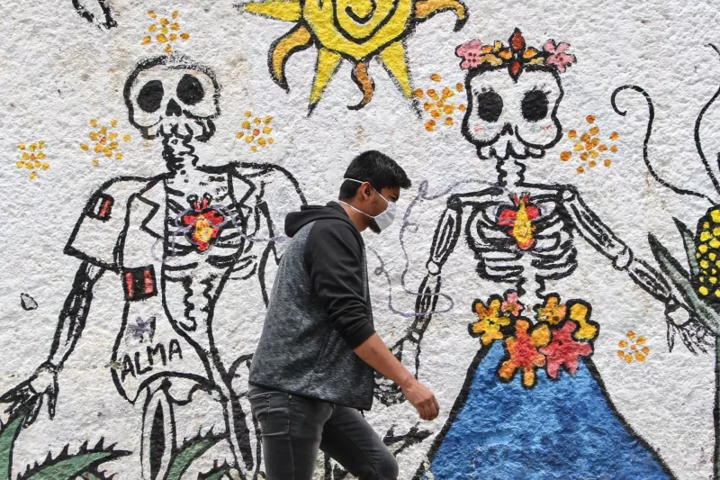 Ciudadanos caminan entre murales alusivos a la muerte en una de las colonias más infectadas por COVID-19.