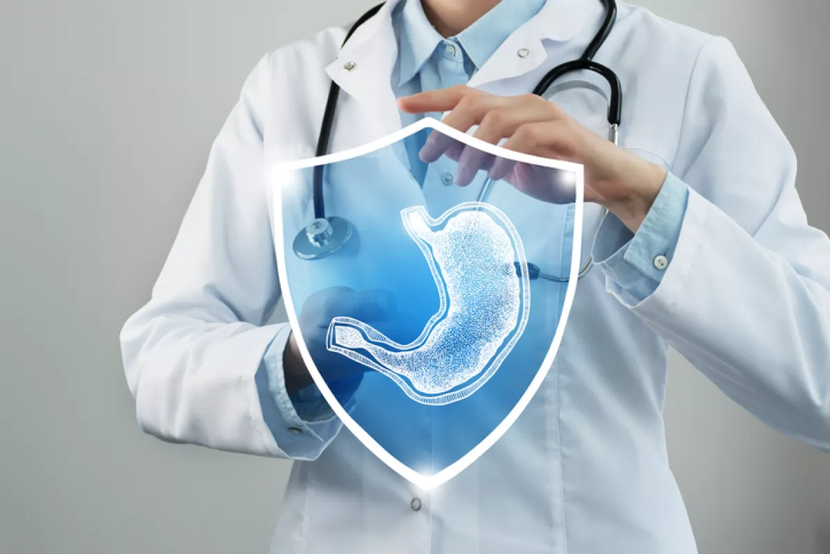 Doctora sosteniendo una imagen de un estómago con escudo de protección.