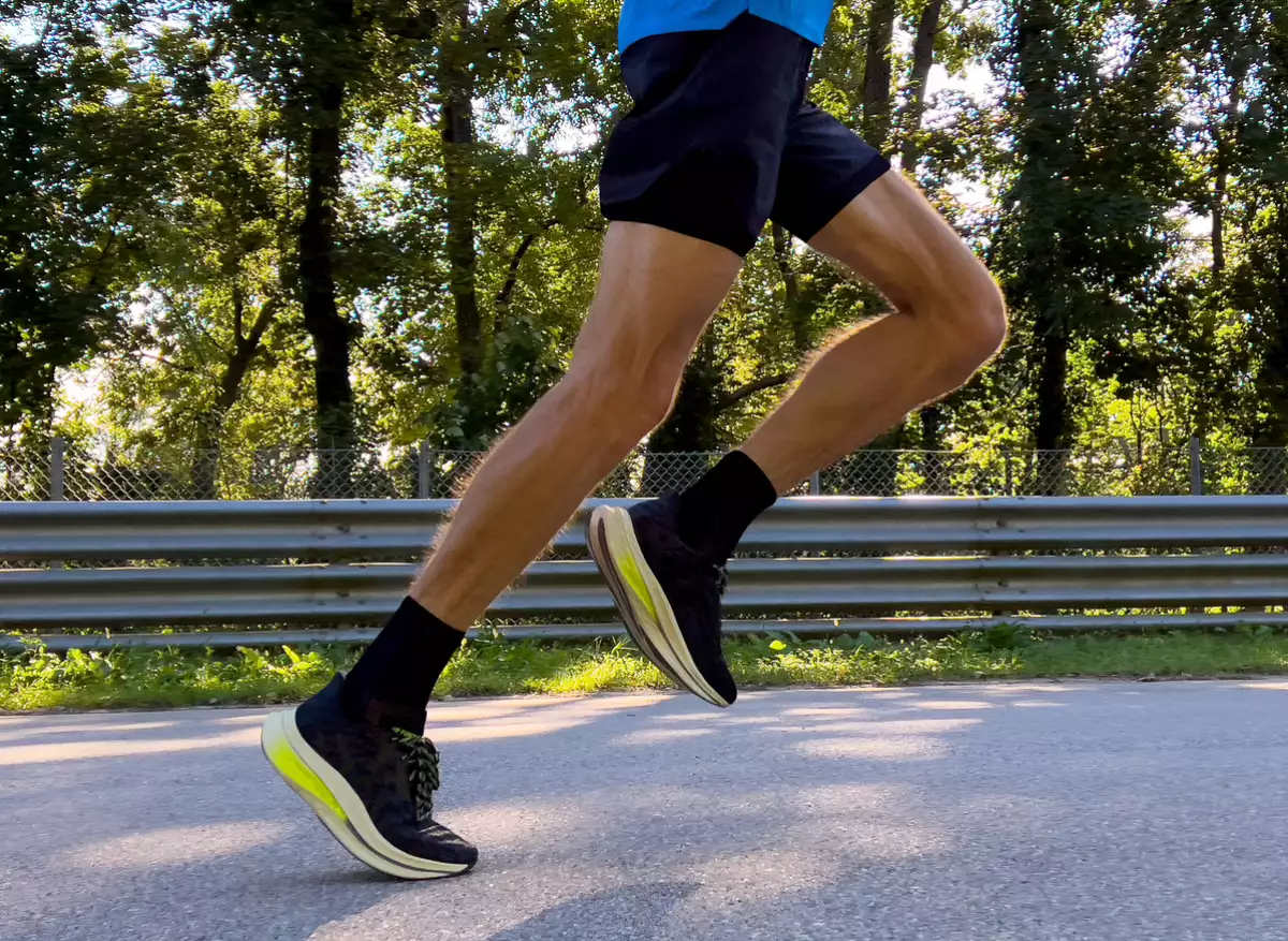 close-up legs male runner running race on road in park