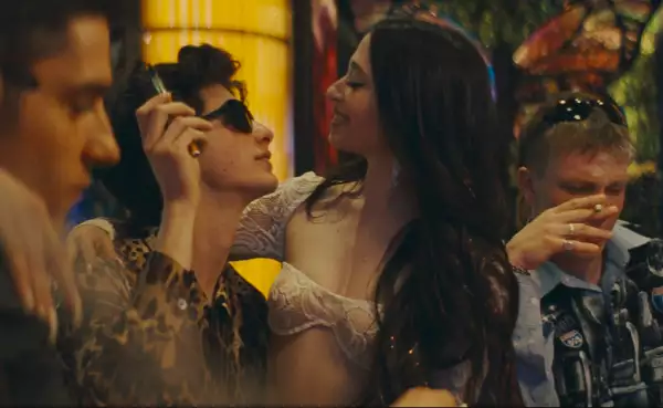 Foto de una escena de la película 'Anora' con los personajes de Ani y Vanya mirándose, ella sentada en las piernas de él.