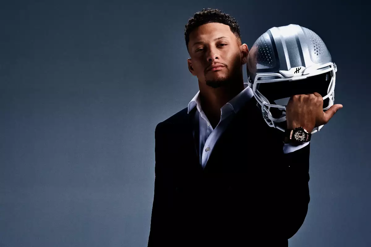 Foto de Patrick Mahomes en traje oscuro cargando un casco de futbol americano plateado y mostrando un reloj Hublot.