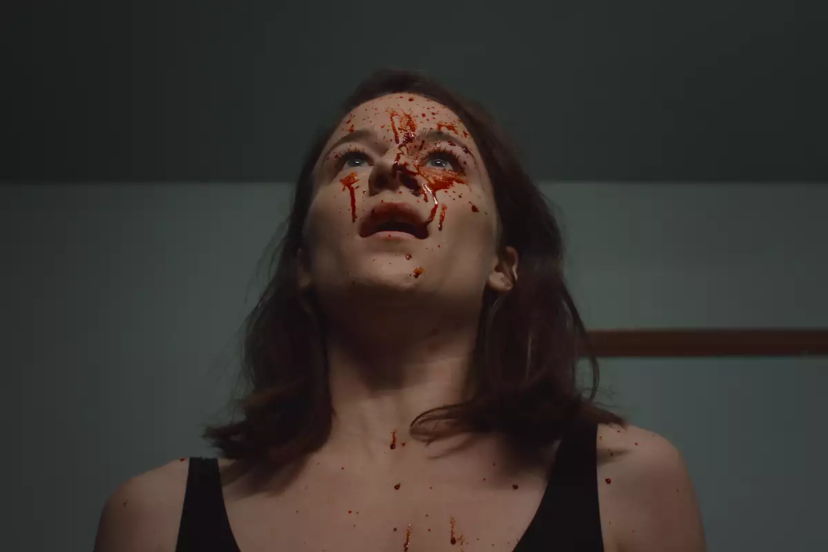 Foto de una escena de la película 'Delicia' en la que se ve al personaje de Esther en close up con la cara salpicada de sangre.