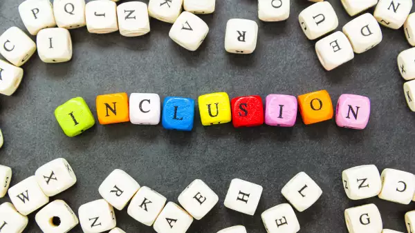 Inclusion text of multi colored cubes on dark background. Inclusive social concept.