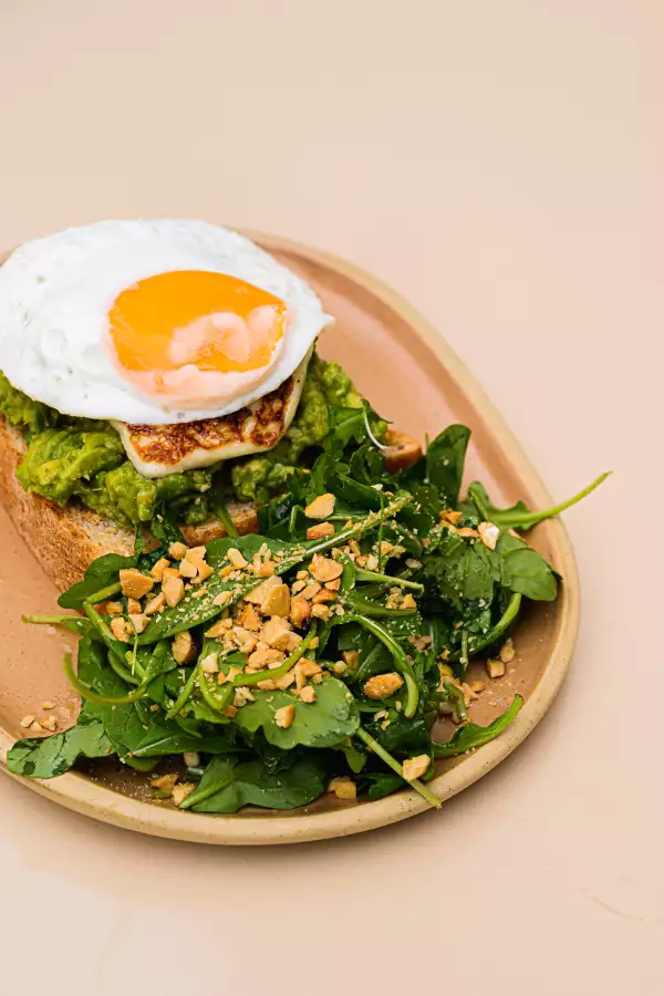 Foto de desayuno mexicano: Avo Toast, tostada de aguacate con un huevo estrellado encima.