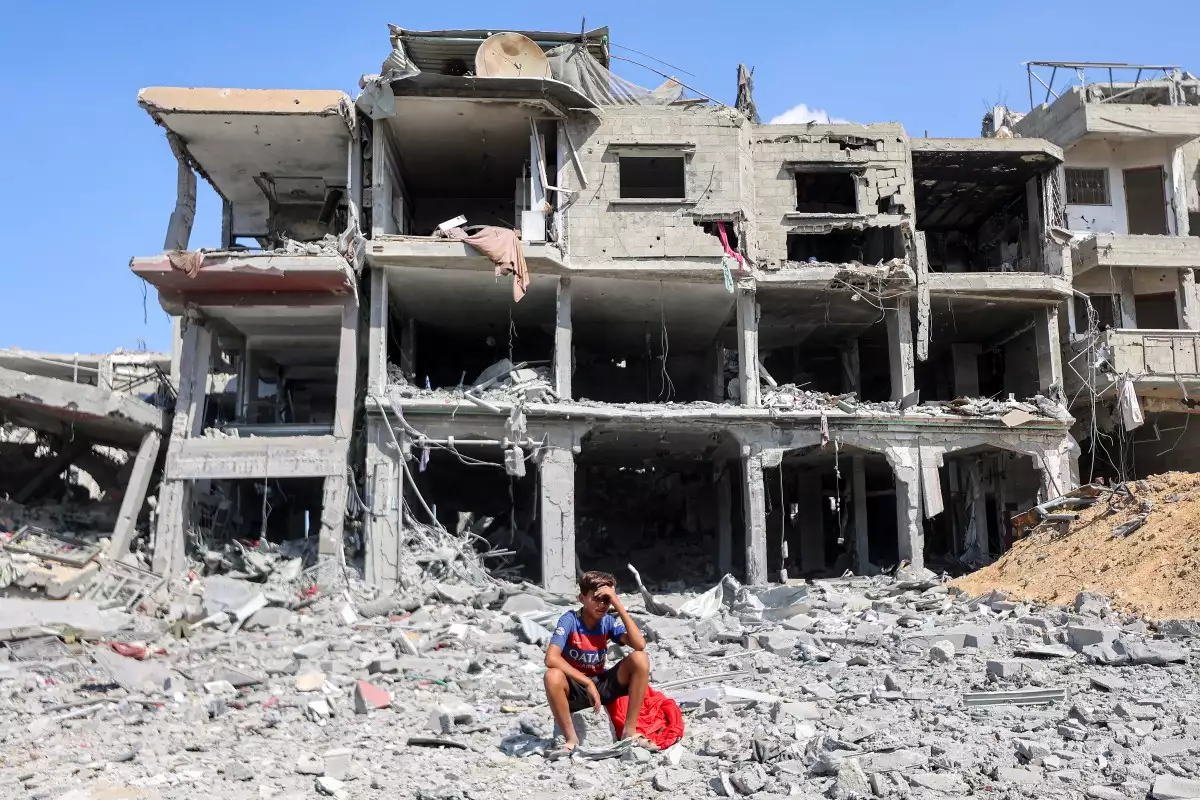 Un niño se sienta entre escombros fuera de un edificio destruido en el centro de Khan Yunis, en el sur de la Franja de Gaza, el 10 de octubre de 2025, mientras los desplazados regresan a sus hogares después de la retirada de las fuerzas israelíes. La agencia de defensa civil de Gaza dijo el 10 de octubre que las fuerzas israelíes han comenzado a retirarse de partes del territorio, particularmente en la ciudad de Gaza y Khan Yunis. Las fuerzas israelíes declararon un alto el fuego y se retiraron de algunas posiciones mientras miles de palestinos desplazados comenzaban a caminar a casa y las familias de los rehenes del 7 de octubre esperaban noticias.