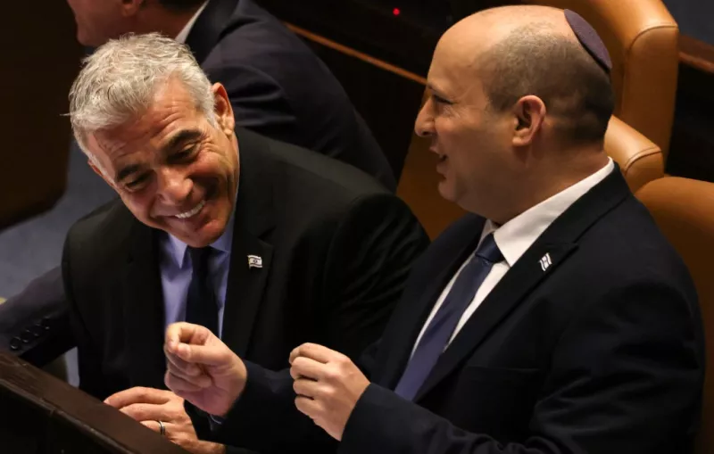 Yair Lapid, ministro de Relaciones Exteriores de Israel, sonríe con el primer ministro saliente Naftali Bennett, durante un encuentro del Knesset (el Parlamento) en Jerusalen. 