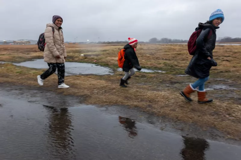 Los migrantes salen de sus tiendas de campaña en Floyd Bennett Field para abordar los autobuses escolares con destino a una escuela secundaria local en previsión de una tormenta con velocidades de viento esperadas de más de 70 mph el 9 de enero de 2024 en el distrito de Brooklyn de la ciudad de Nueva York.