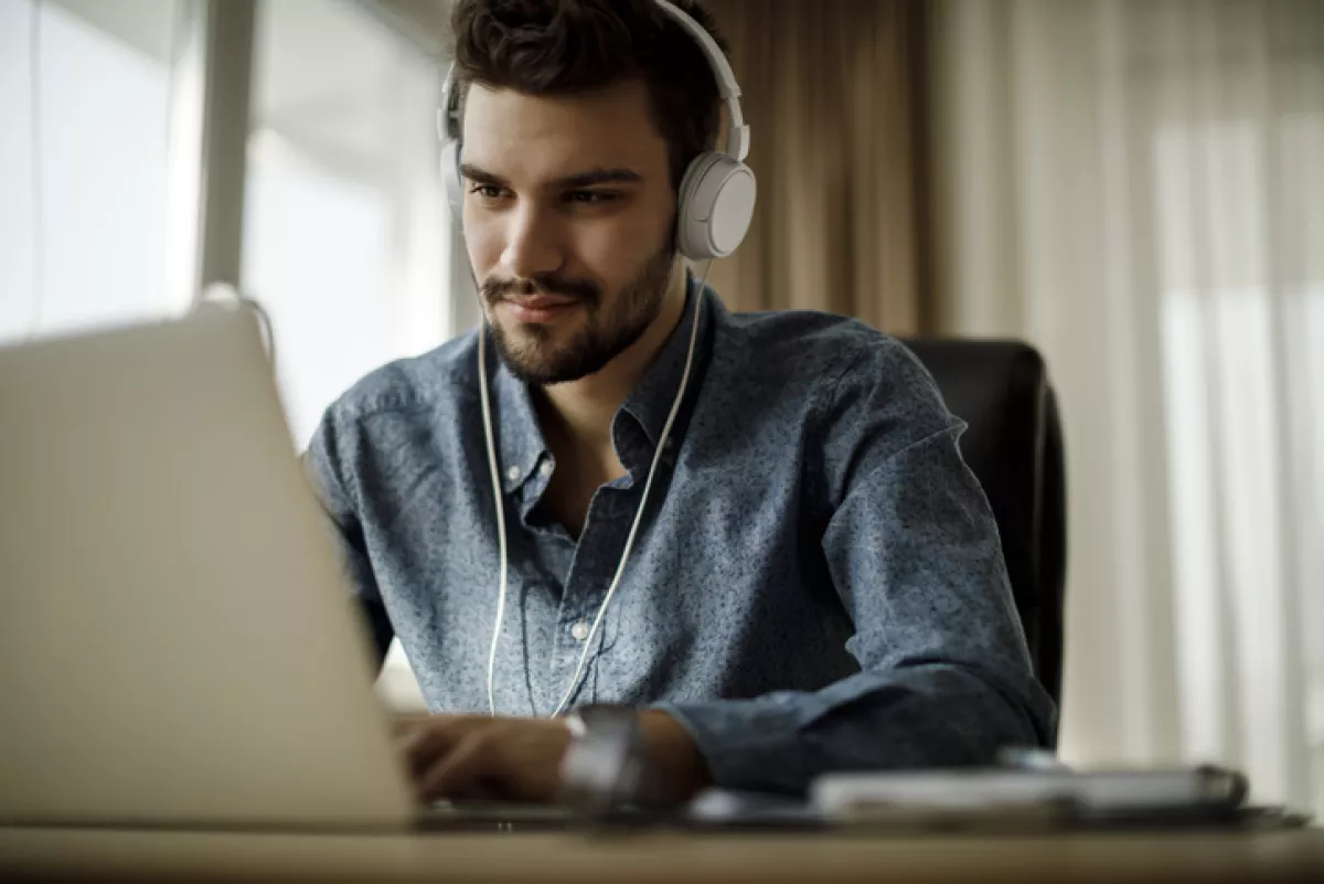 Young man using laptop and listening to music