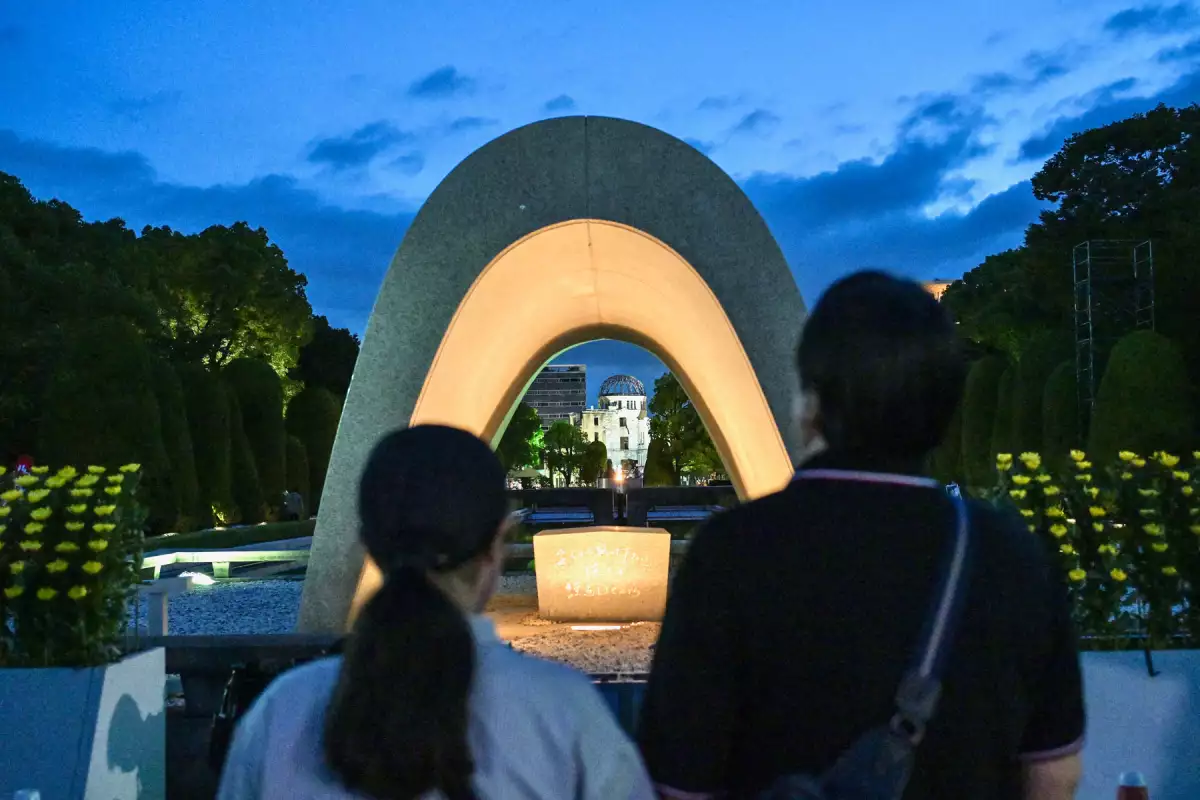 Los visitantes rezan por las víctimas de la bomba atómica frente al Cenotafio Memorial en el Parque Memorial de la Paz antes del servicio conmemorativo para conmemorar el 80 aniversario del primer ataque a la bomba atómica del mundo, en la ciudad de Hiroshima a principios del 6 de agosto de 2025.