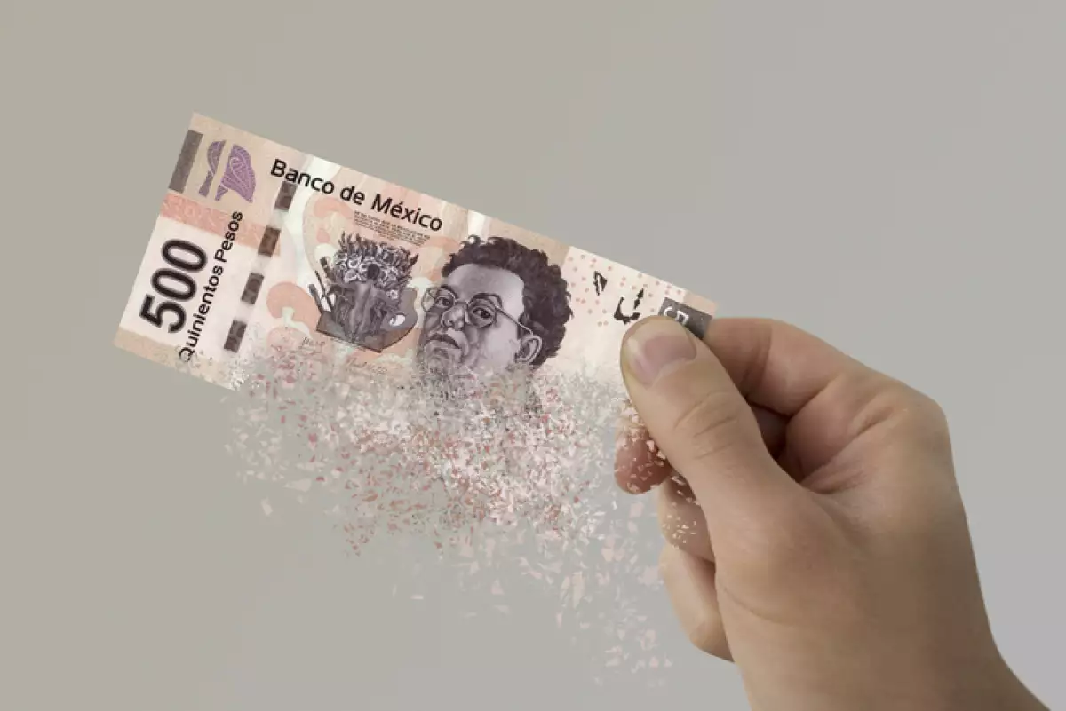Mexican Pesos bill pulverizes in a man's hand.