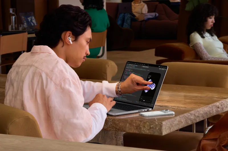 Usuario tocando la pantalla de la MacBook Pro PROLED XDR, la cual ahora tiene funciones táctiles.