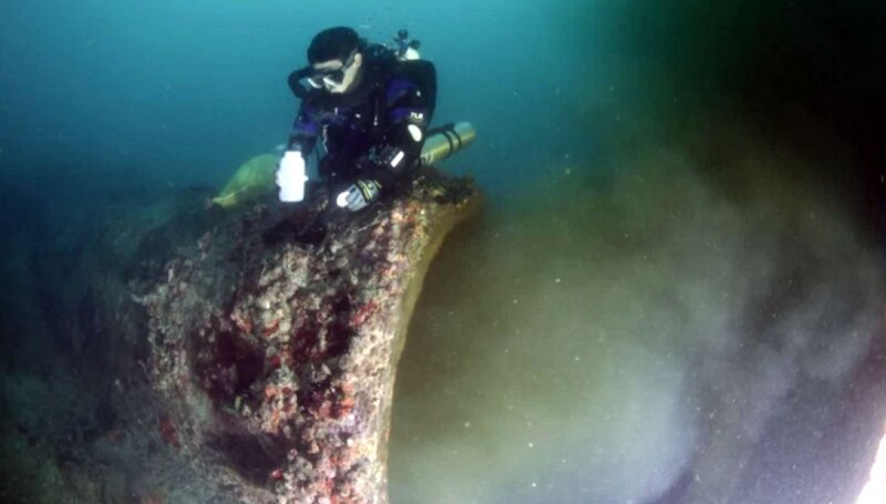 Un buzo recolecta muestras del drenaje.