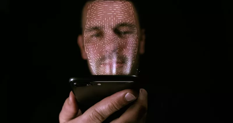Male using his smart phone with facial recognition unlock. 3D mesh print is projected onto his face.