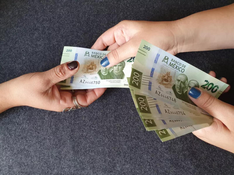 Una persona recibe billetes de 200 pesos.