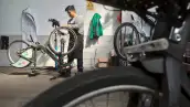 Un hombre repara una bicicleta de Ecobici. 