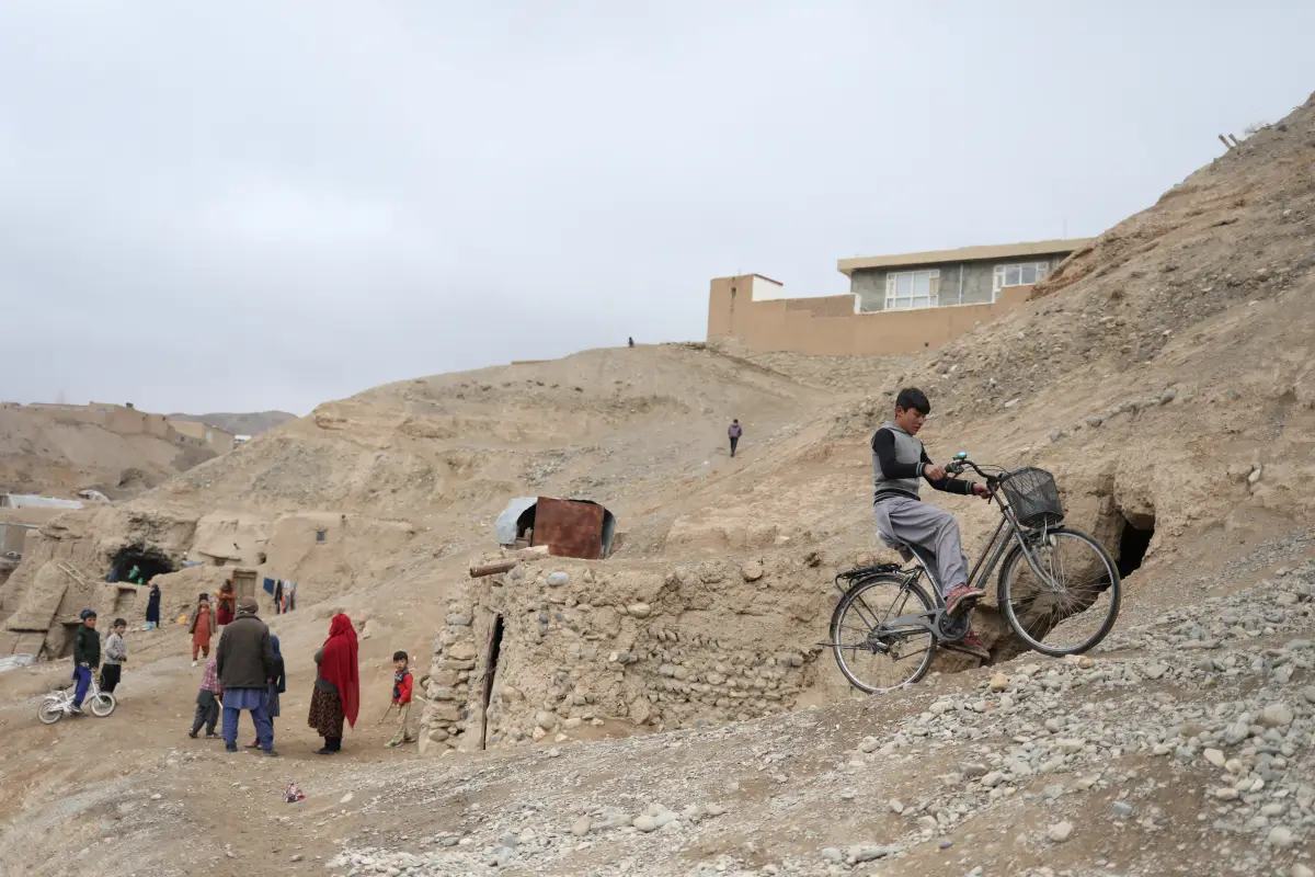 Un niño conduce una bicicleta cerca de unas casas en una colina en Bamiyan, Afganistán. 