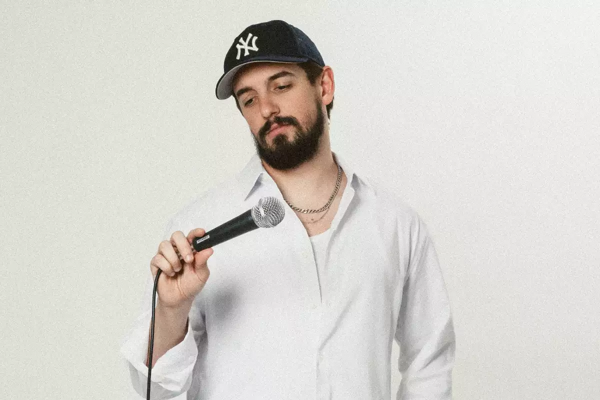 Foto del comediante Nacho Redondo con gorra y un micrófono en mano.