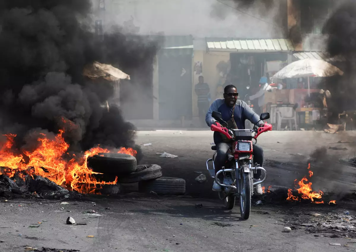 Un motociclista reacciona mientras conduce a través de una barricada en llamas, una de muchas en varios vecindarios que obligaron a los residentes a refugiarse, en Puerto Príncipe, Haití, el 18 de enero de 2024.