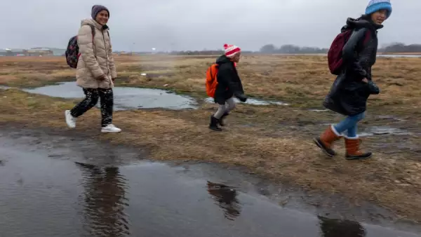 Los migrantes salen de sus tiendas de campaña en Floyd Bennett Field para abordar los autobuses escolares con destino a una escuela secundaria local en previsión de una tormenta con velocidades de viento esperadas de más de 70 mph el 9 de enero de 2024 en el distrito de Brooklyn de la ciudad de Nueva York.