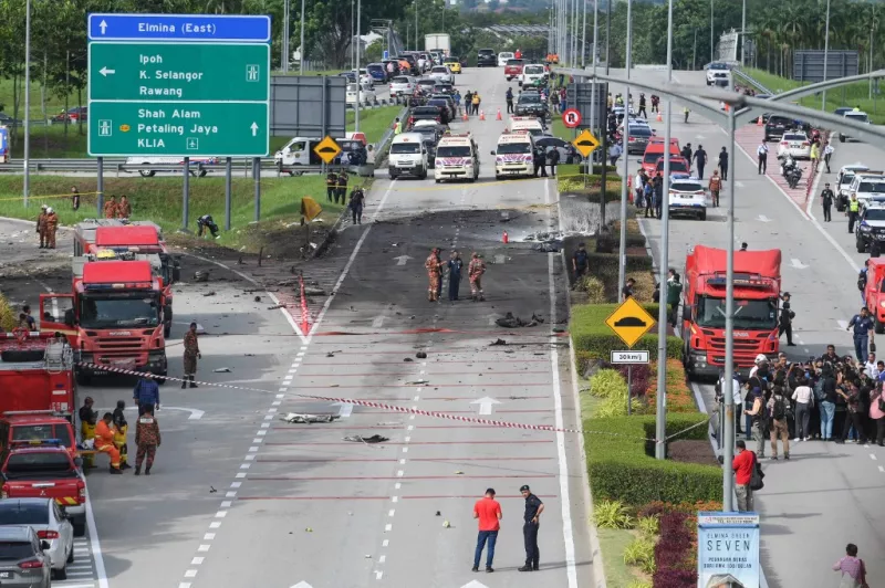 Miembros del departamento de bomberos y rescate inspeccionan el lugar del accidente de un avión en una calle en Shah Alam, en el estado de Selangor, Malasia, el 17 de agosto de 2023.