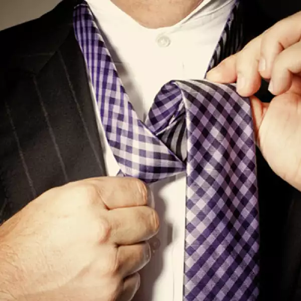 Pasar el extremo más ancho de la corbata por atrás y hacer una especie de nudo, jalándolo hacia arriba y un lado.