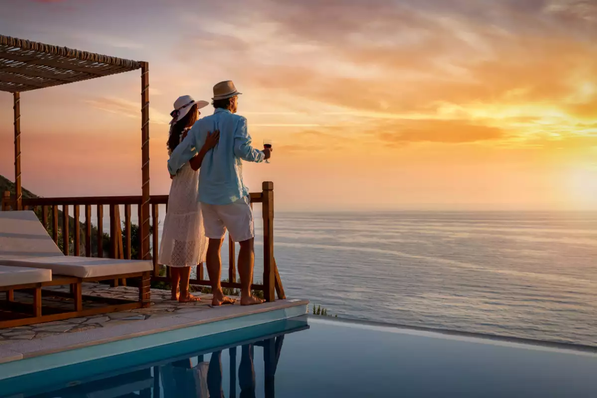 Una pareja romántica en vacaciones de verano disfruta de la puesta de sol sobre el mar mediterráneo junto a la piscina