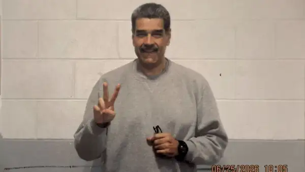 Con un fondo de color gris y blanco, Nicolás Maduro aparece con una sudadera gris, haciendo la señal de paz con una mano, sosteniendo sus lentes y un reloj en su muñeca izquierda.