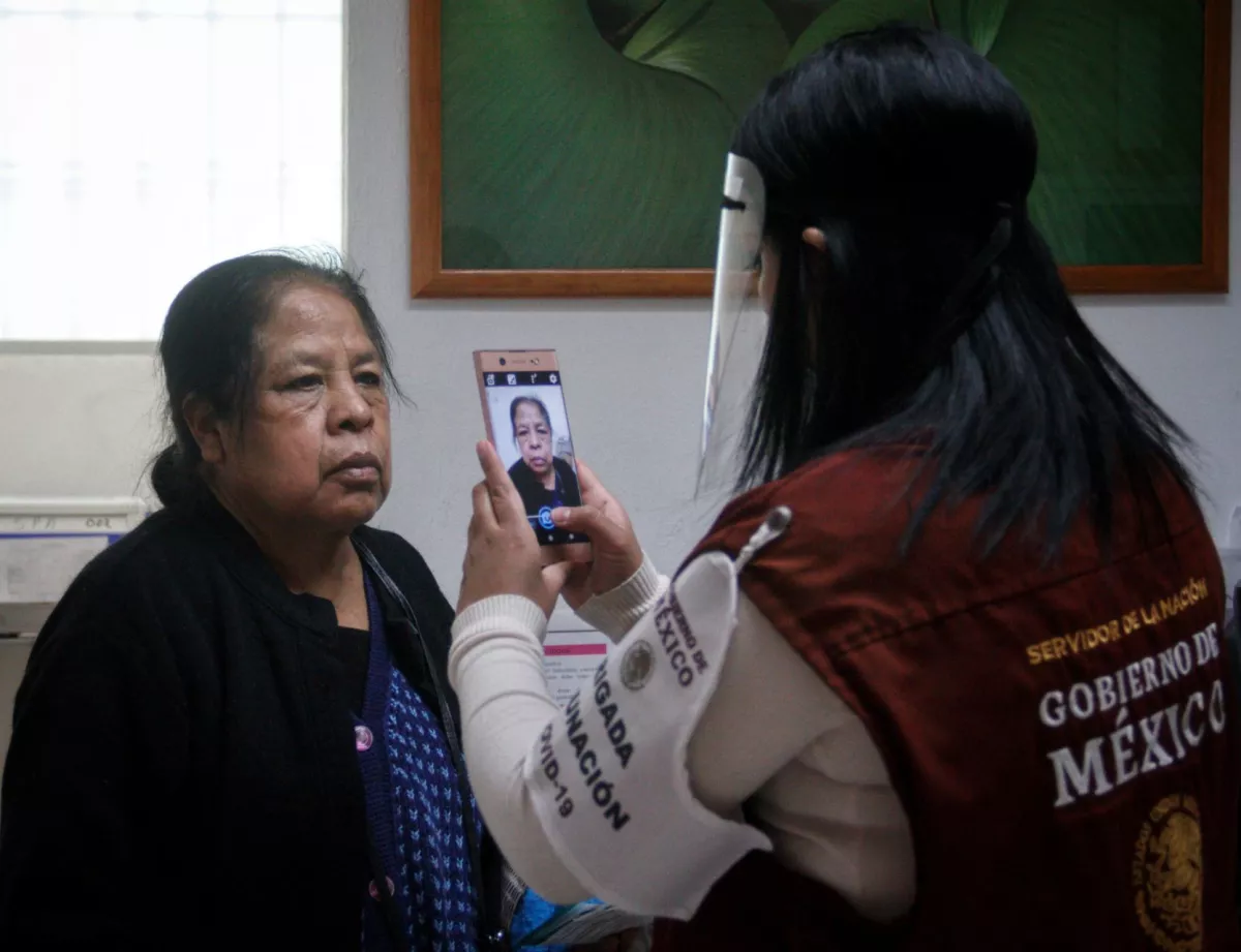 Servidores de la nación toman fotografías a las personas de tercera edad ya que pasaron los filtros de entrega de papeles previo a ser vacunadas con la primera de dos dosis contra COVID-19
