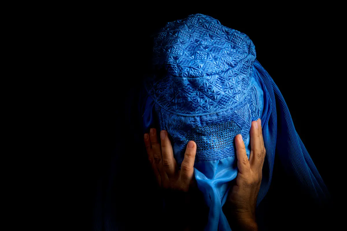 Mujer afgana triste con la cabeza gacha viste una burka. 