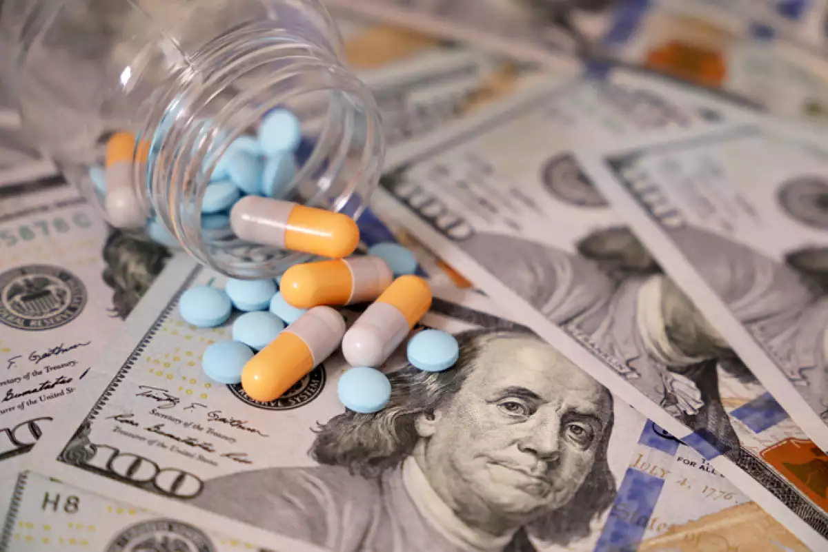 Pills and capsules in a bottle on US dollars bills
