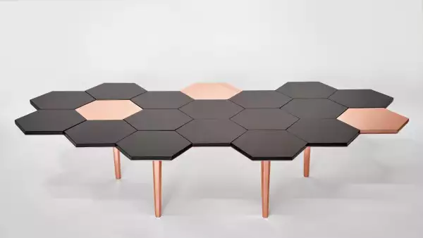 Se aprecia la mesa Honeycomb, creación de Sten Studio, misma que tiene una forma de panal de abeja en colores negro y dorado.