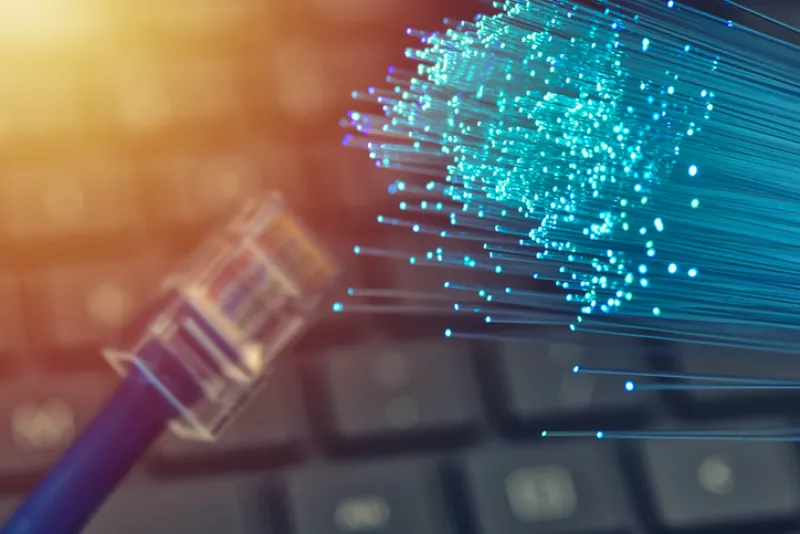 Fiber optics in blue, close up with ethernet and keyboard background, warm lens flare