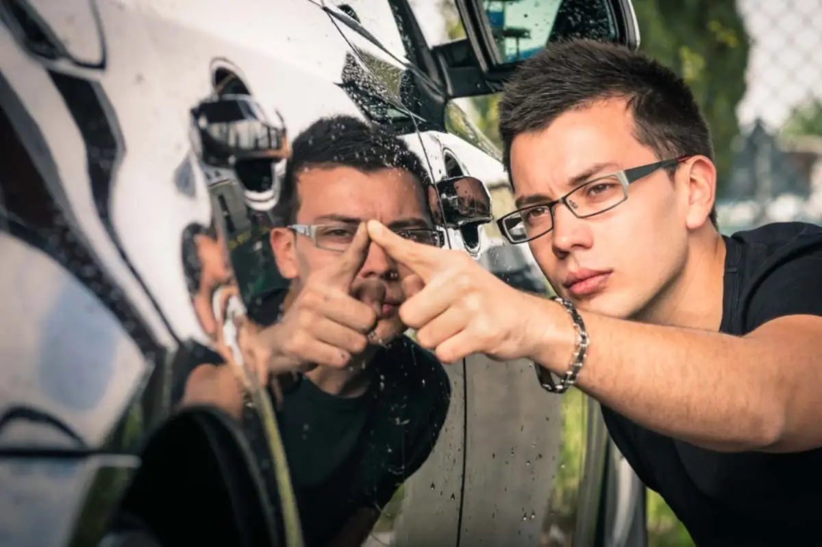 Joven revisando un auto. Estas son las cosas que se deben revisar antes de comprar un carro usado. 