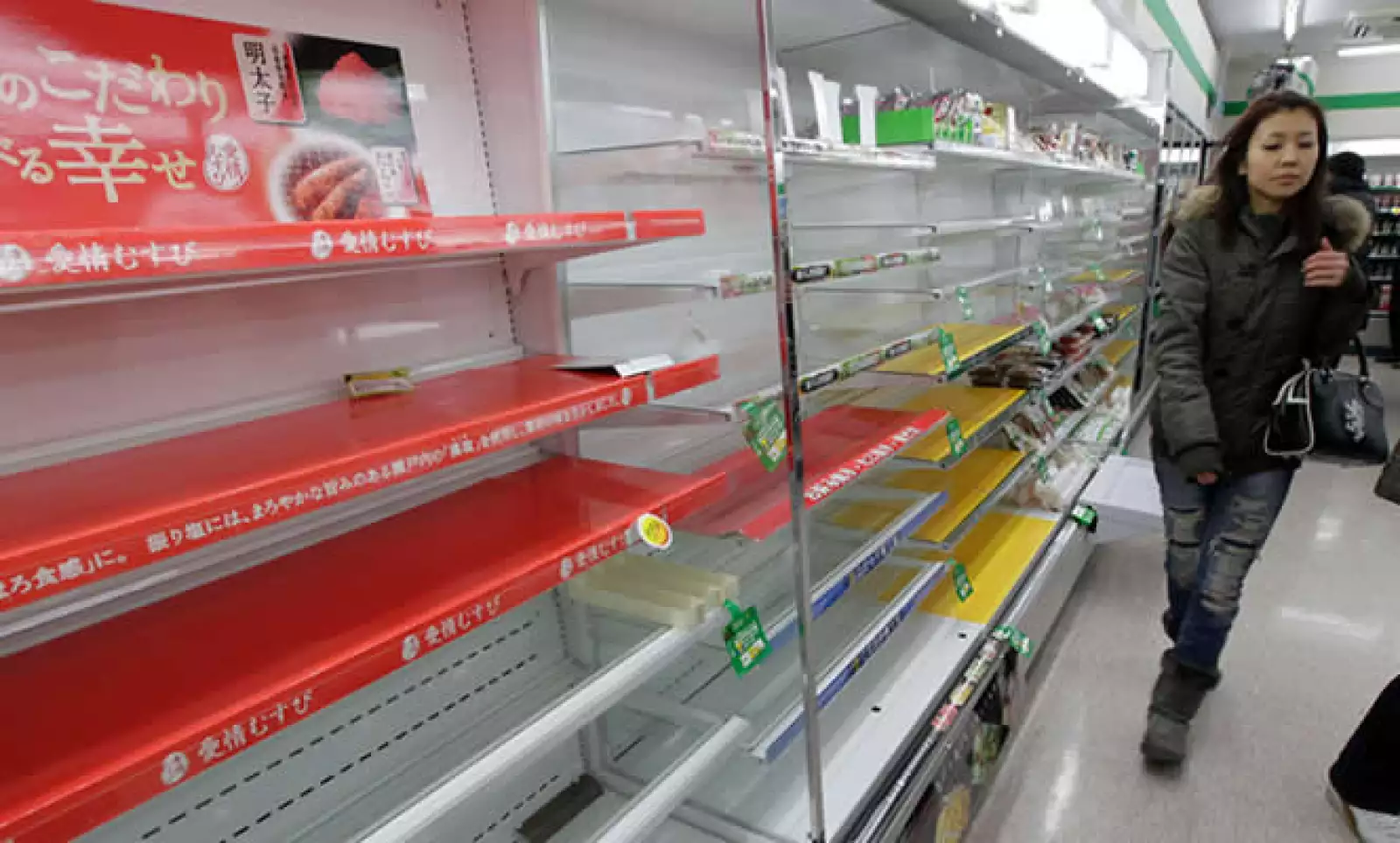 Una mujer busca provisiones en una tienda de Tokio, a pesar de que las tiendas muestran muy poca comida y agua.