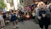 Una joven intercambia poses con una botarga del Dr. Simi durante un reto de farmear aura frente a Café Simi en Playa del Carmen, mientras los asistentes graban la activación con sus teléfonos.