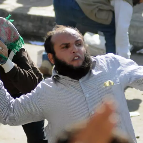 un manifestante laza una piedra