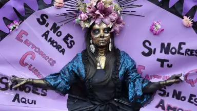 Una mujer desfila con una lectura escrita "Si no ahora, ¿cuándo? Si no es aquí, ¿dónde? Si no eres tú, ¿quién? Si no con amor y rebelión, ¿cómo? Durante una manifestación con motivo del Día Internacional de la Mujer en Madrid el 8 de marzo de 2026