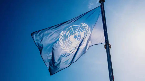 UN flag waved against the sun and blue sky.