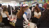 Cuatros mujeres con blusas blancas y tres hombres con camisa alrededor de una mesa donde hay papeles .jpg