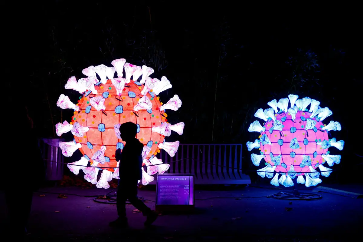 Un visitante pasa junto a un modelo iluminado de coronavirus (COVID-19) mientras visita la exposición "Mini-Mundos en el Camino de la Iluminación" (Mini-Mondes en voie d'illumination) durante la vista previa del Festival de la Luz en el Jardin des Plantes (Jardín botánico) en París, Francia, 12 de noviembre de 2022