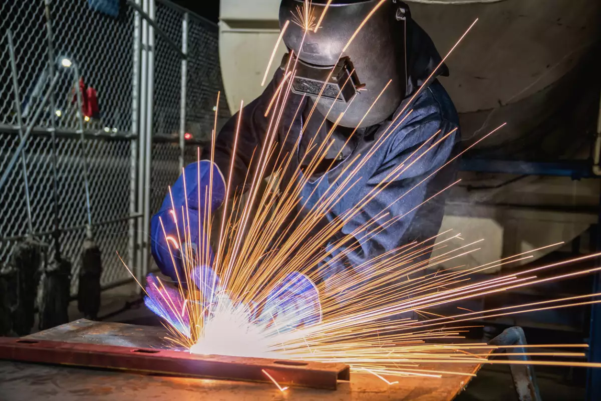 Industrial worker is welding in factory
